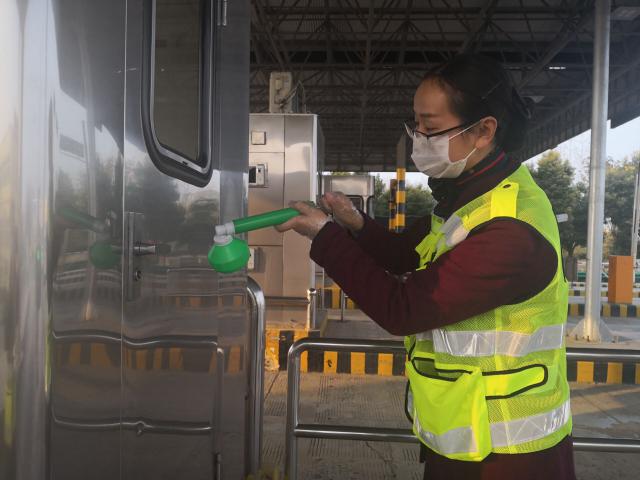 界阜蚌公司太和站團(tuán)員正在認(rèn)真地給收費亭門把手消毒.jpg